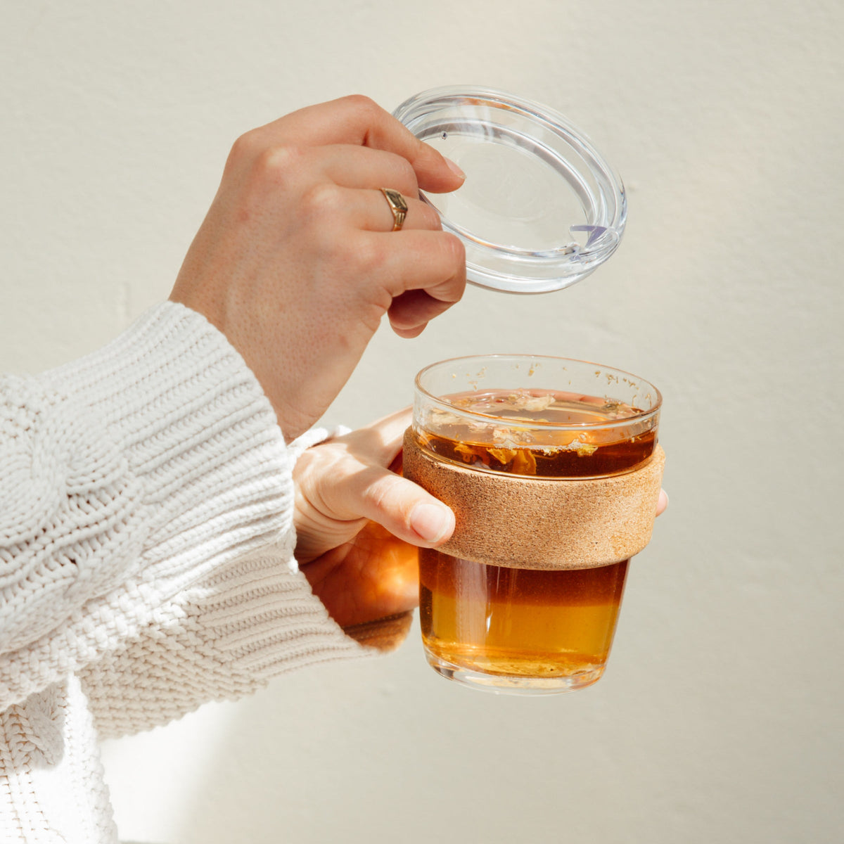 Hands holding a KeepCup Brew Cork QuickSip 340ml filled with golden tea