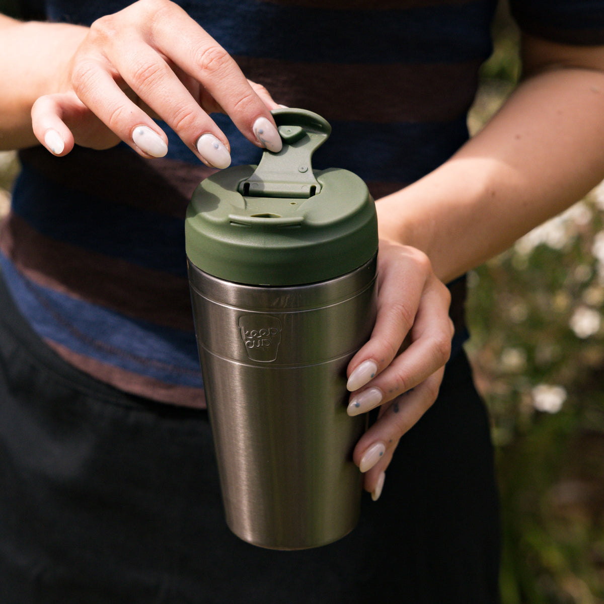 Person holding a KeepCup Commuter 454ml in Nitro Pine, showing the flip lid