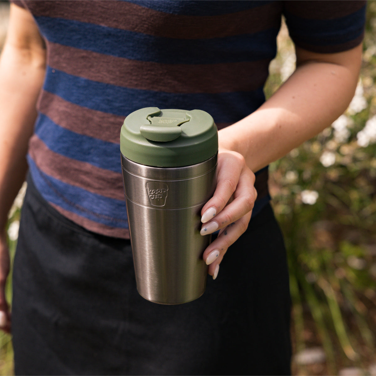 Hand holding a KeepCup Commuter 454ml in Nitro Pine outdoors