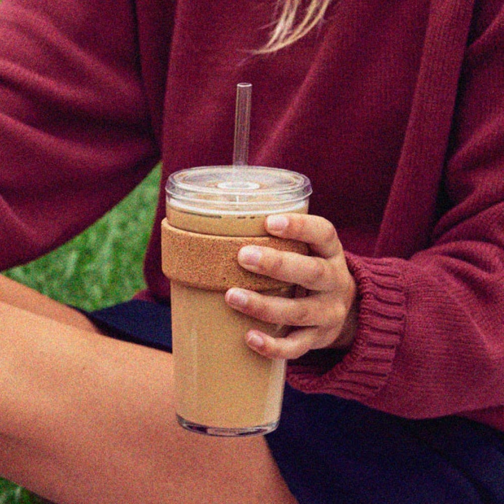 Hand holding a KeepCup Cold Cup Cork 454ml filled with iced coffee