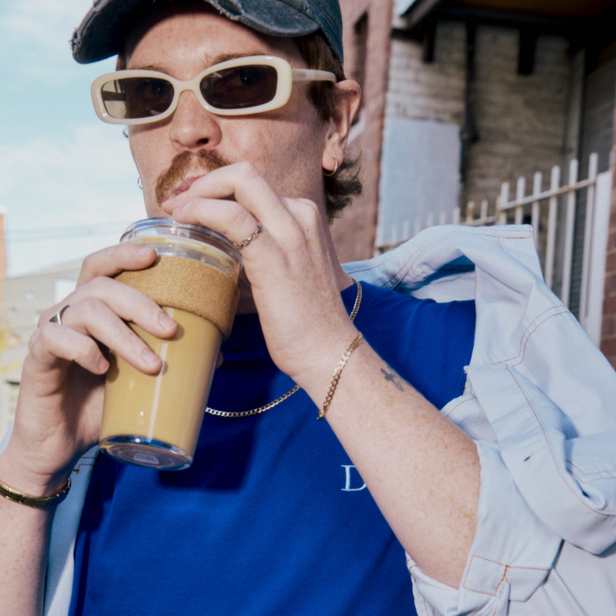 Man in sunglasses and a cap sipping iced coffee from a KeepCup Cold Cup Cork 454ml