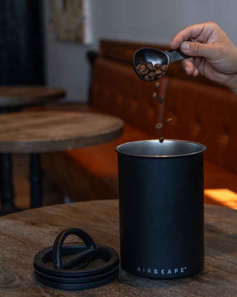 Pouring coffee beans into black Airscape canister