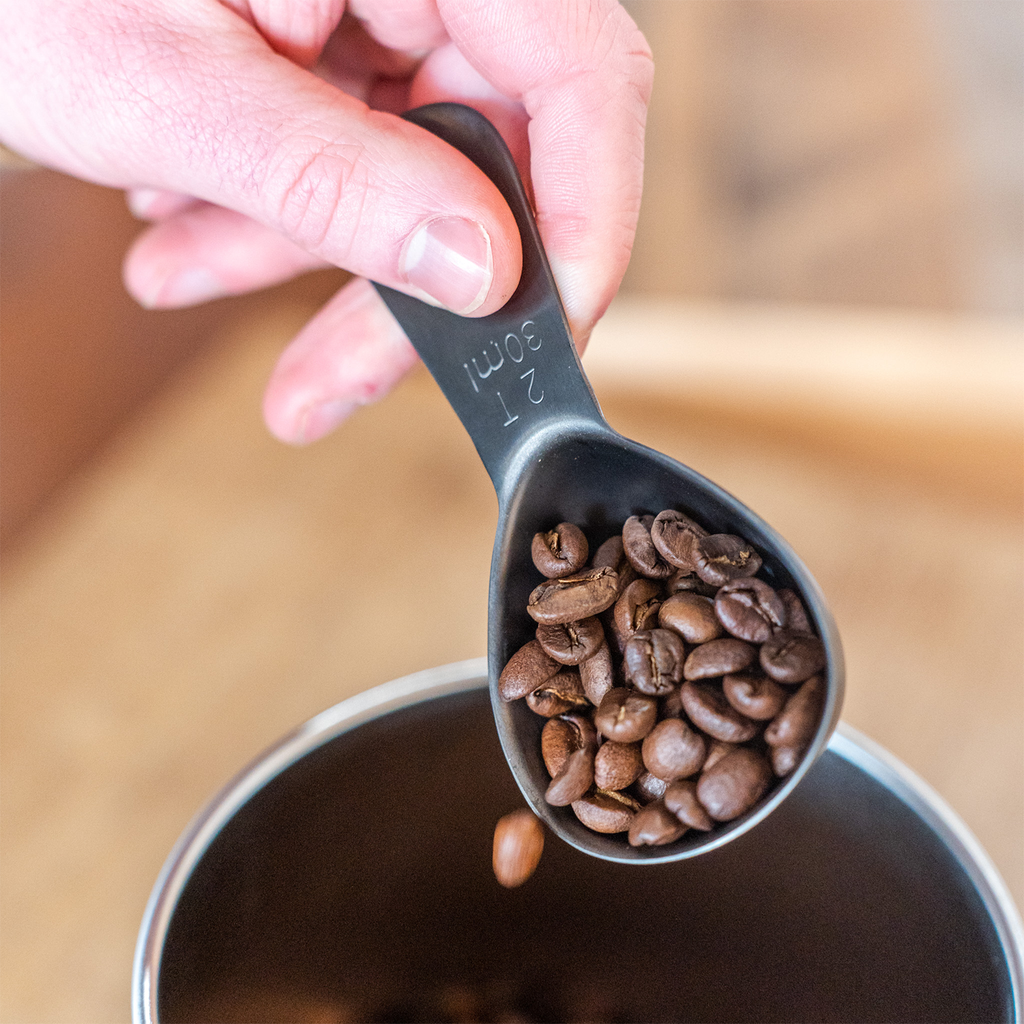 Airscape black coffee scoop pouring beans into canister