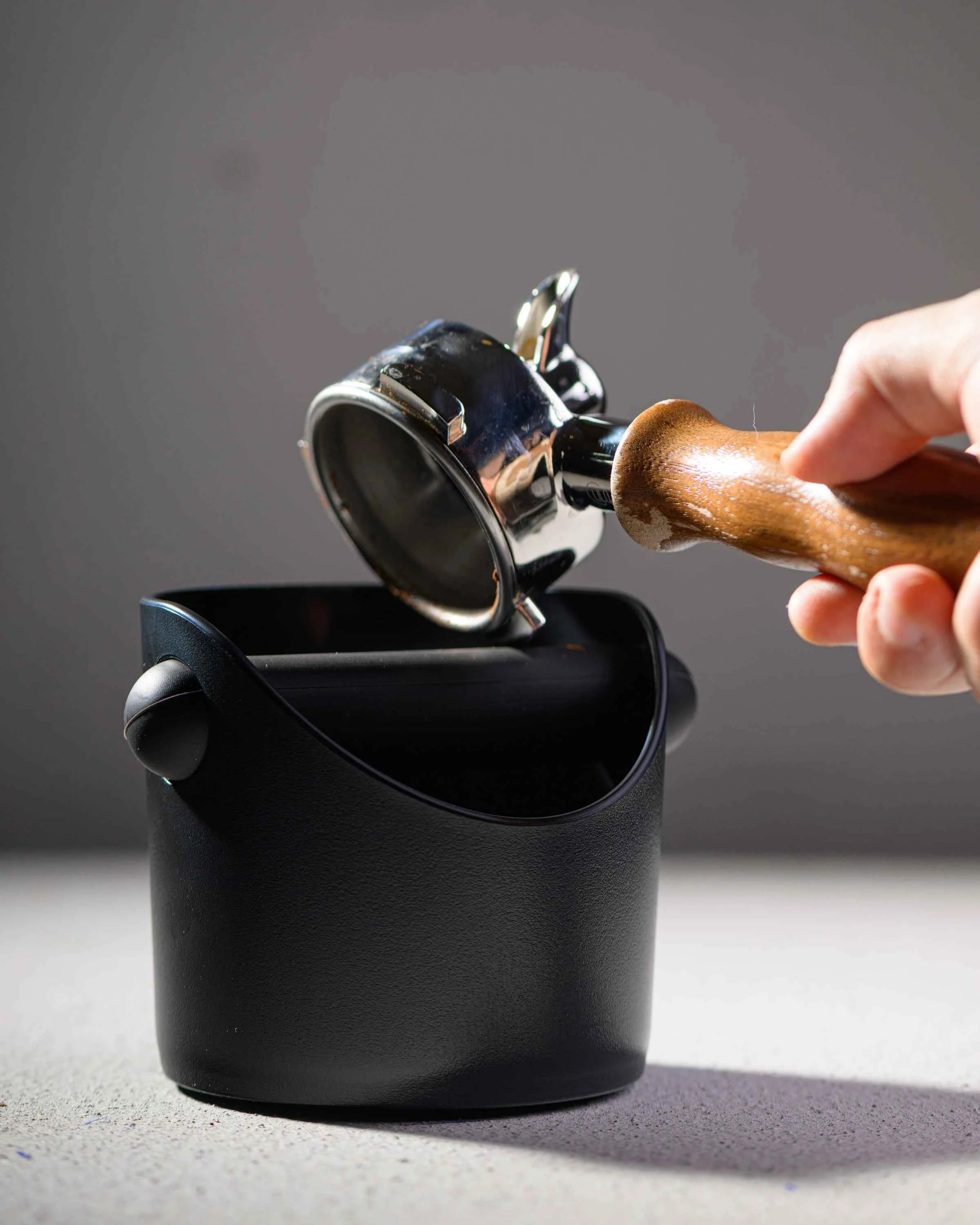 Knocking an espresso puck into the matte black knock box