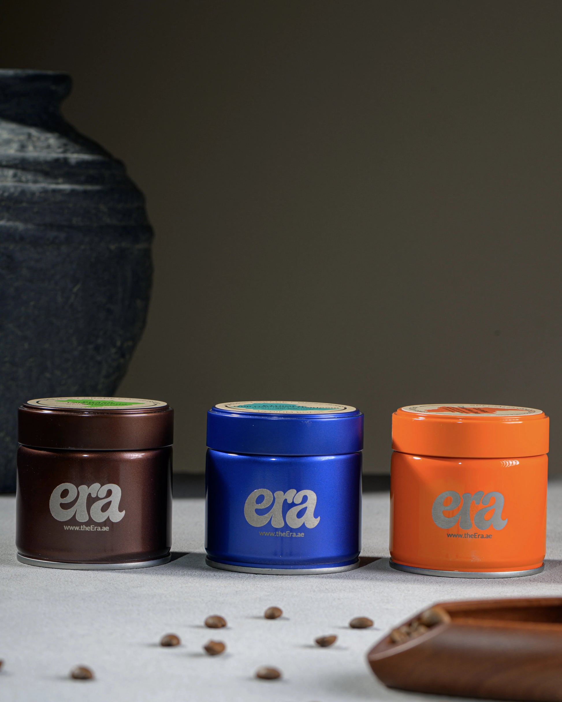 Era coffee tins in brown, blue, and orange with engraved logo