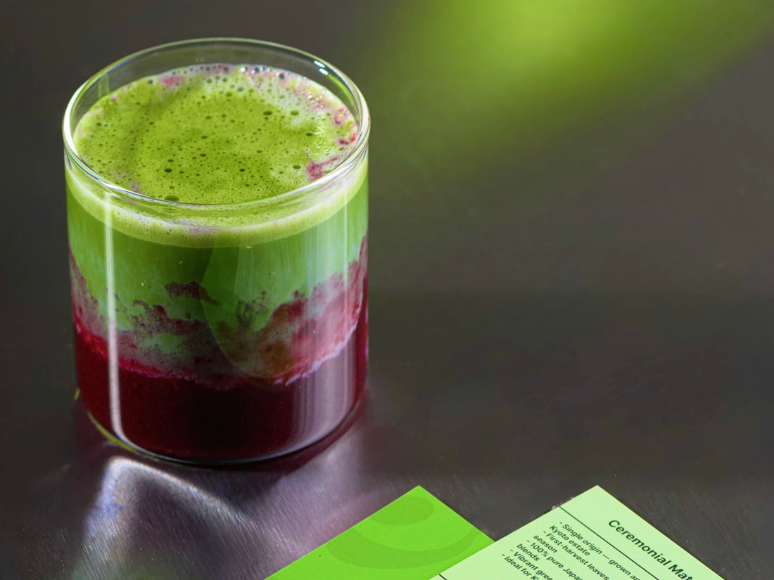 Layered berry matcha drink in a glass on a dark table beside Era recipe cards