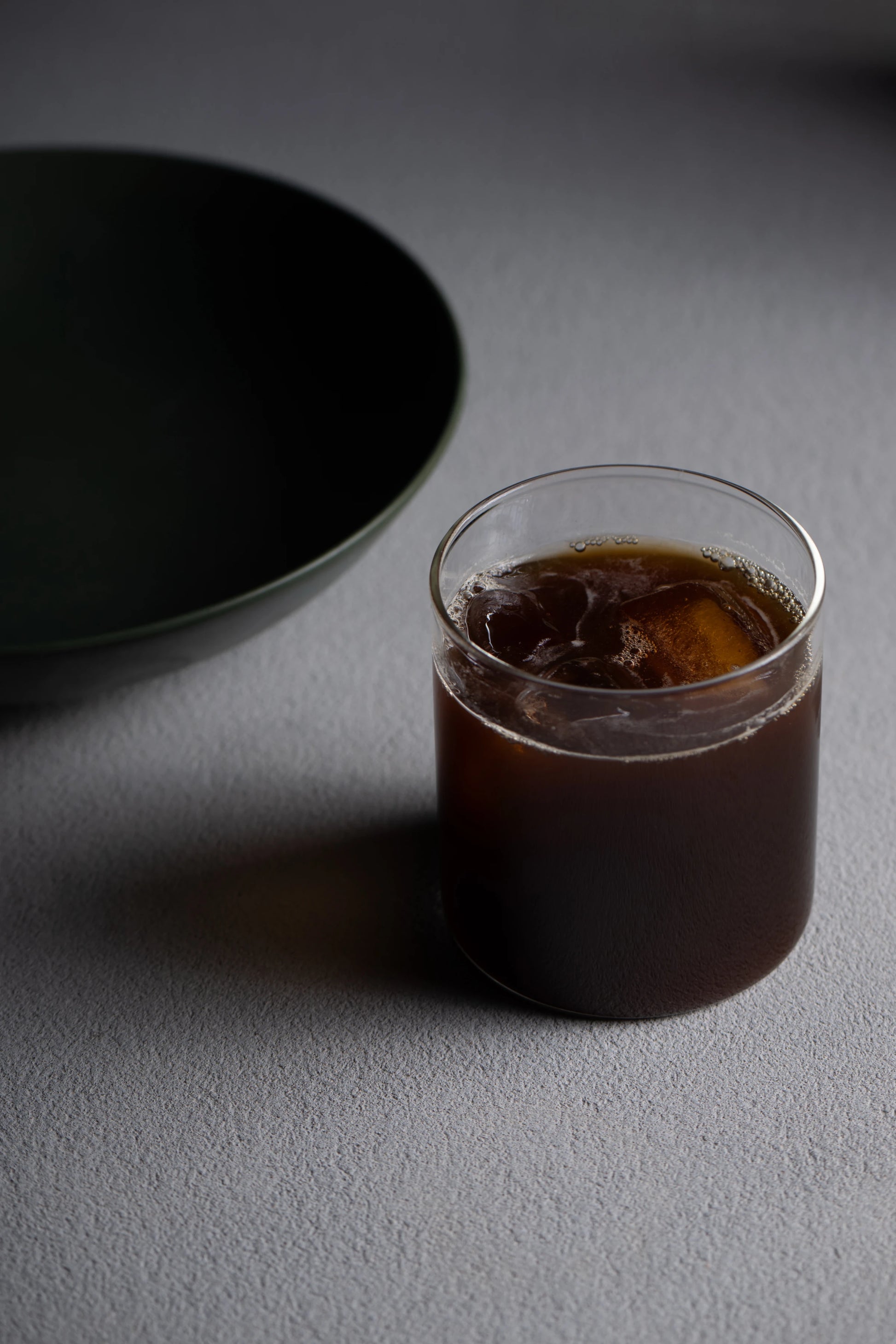 Iced Era coffee in a glass beside a dark green bowl