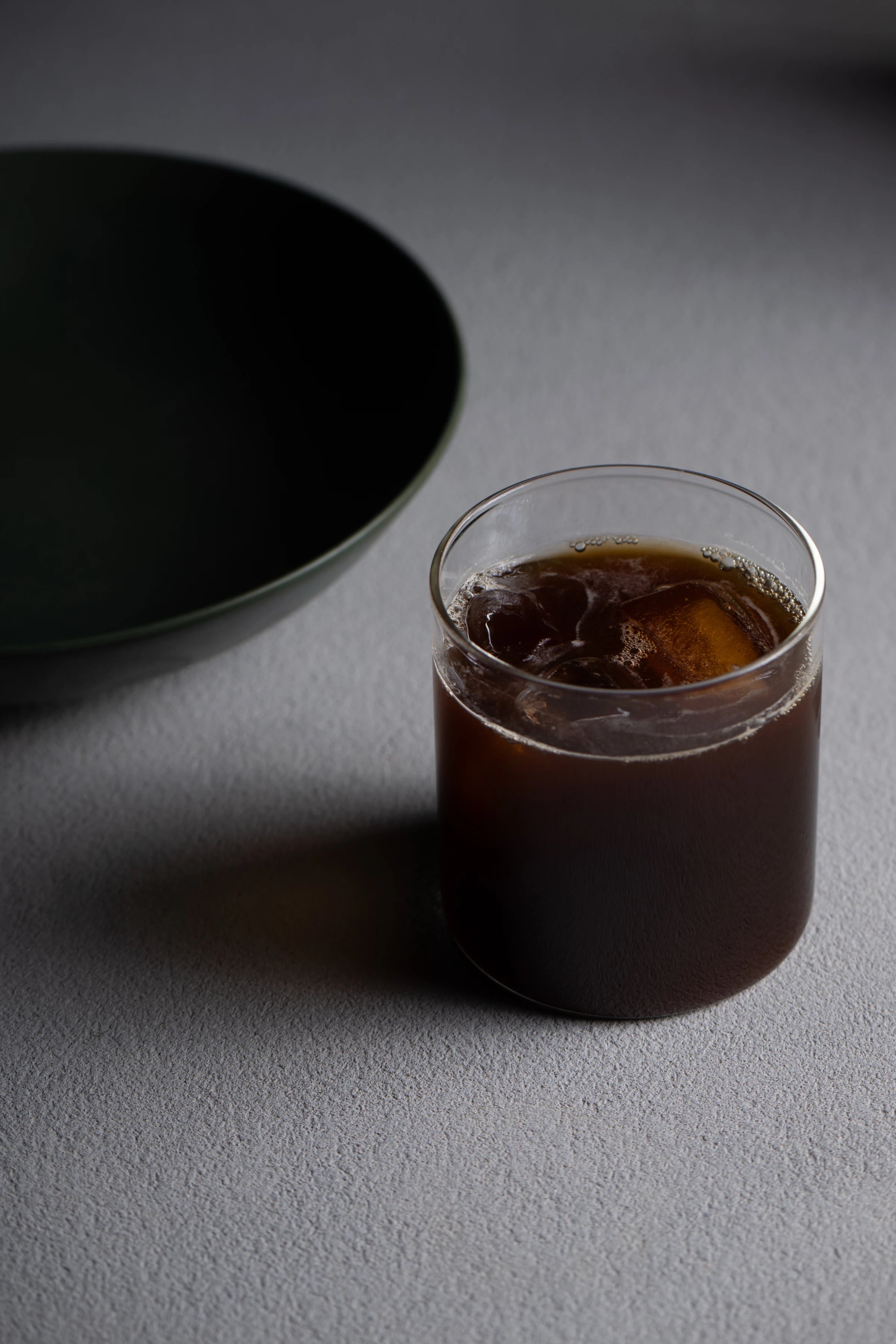 Iced Era coffee in a glass beside a dark green bowl