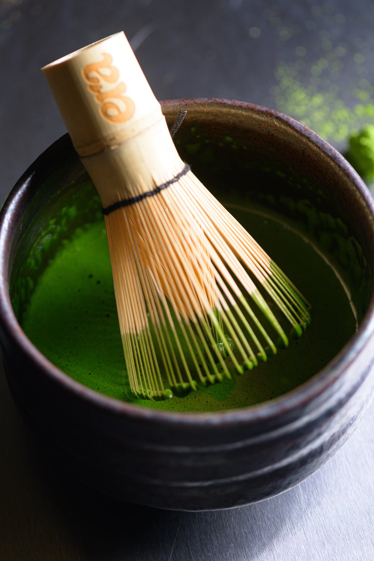 Freshly whisked ceremonial Uji matcha with Era bamboo chasen in a dark bowl