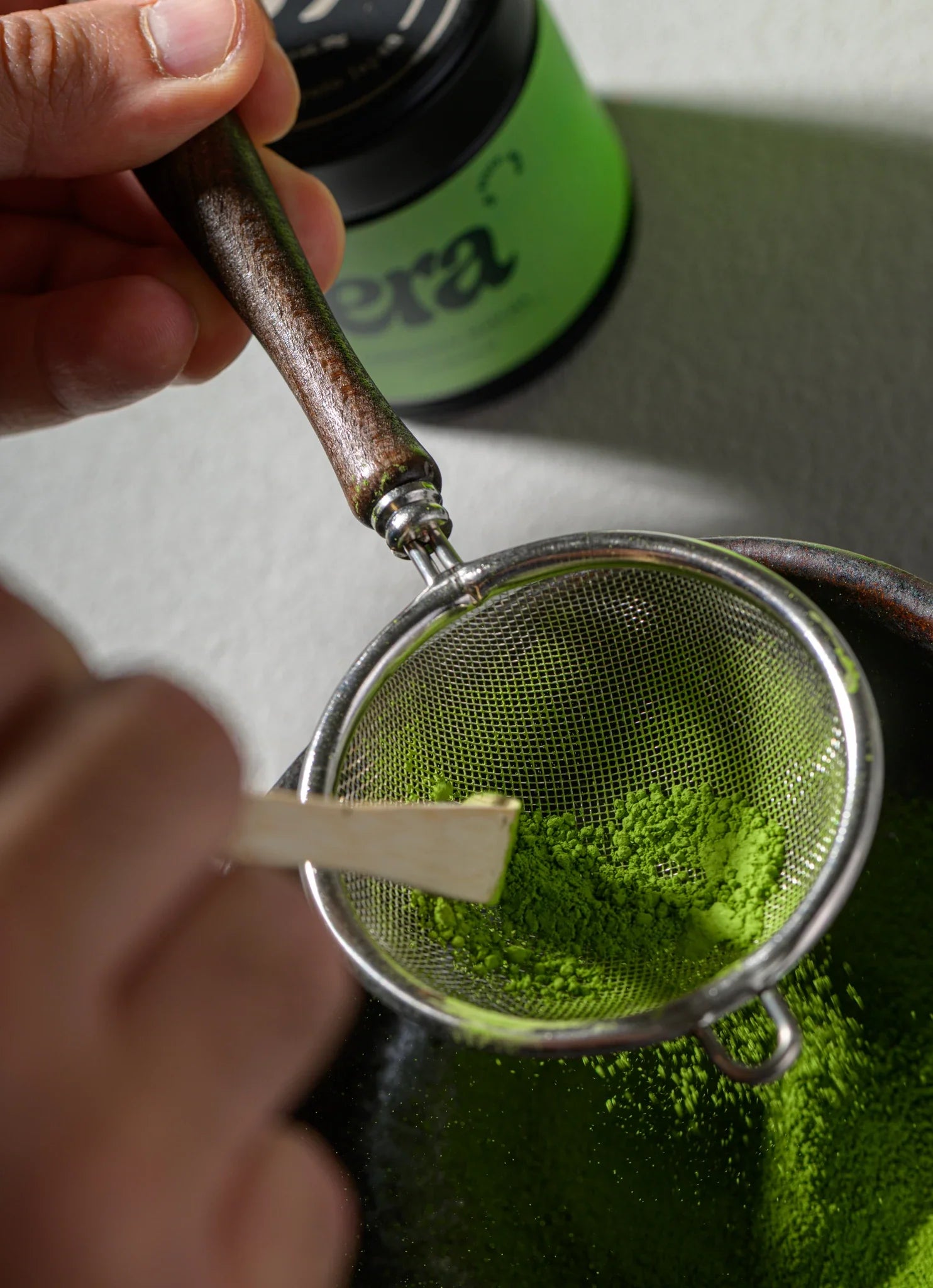 Pressing matcha through the Furui sifter with a bamboo chashaku