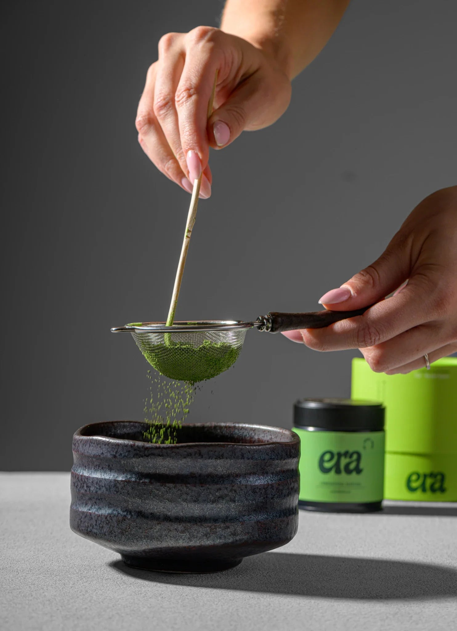Sifting Era ceremonial matcha through the Furui into a dark matcha bowl