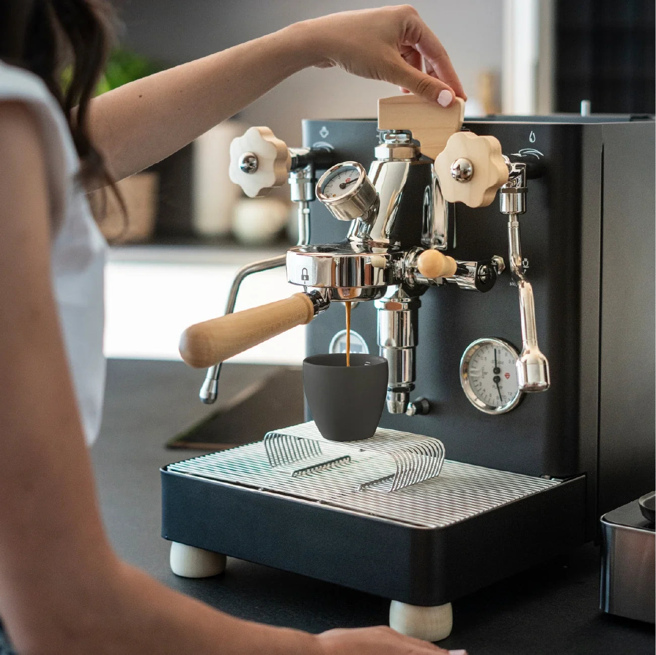 Black Lelit coffee cup on the cup rack of a Lelit espresso machine during extraction