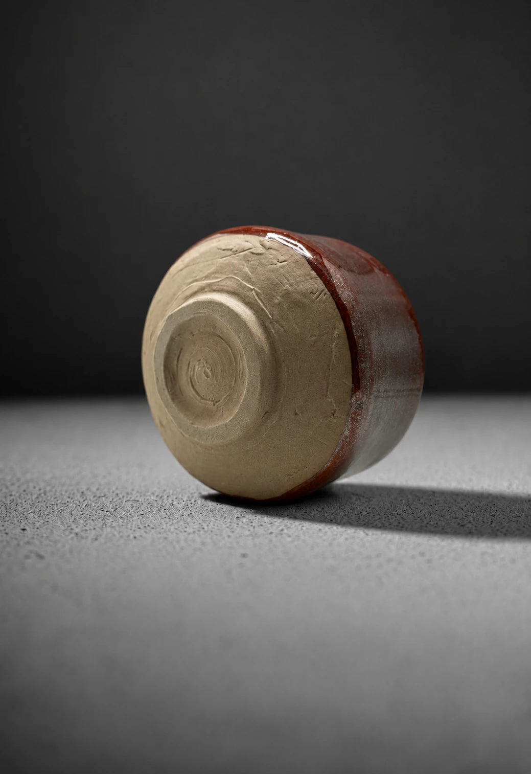 Base of Shin Akagane rust matcha bowl showing wide unglazed clay foot and glaze line detail