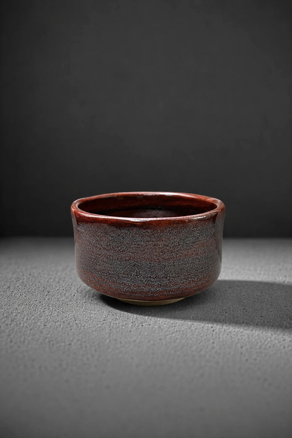 Shin Akagane matcha bowl in rusted copper glaze with silver mist on dark grey background
