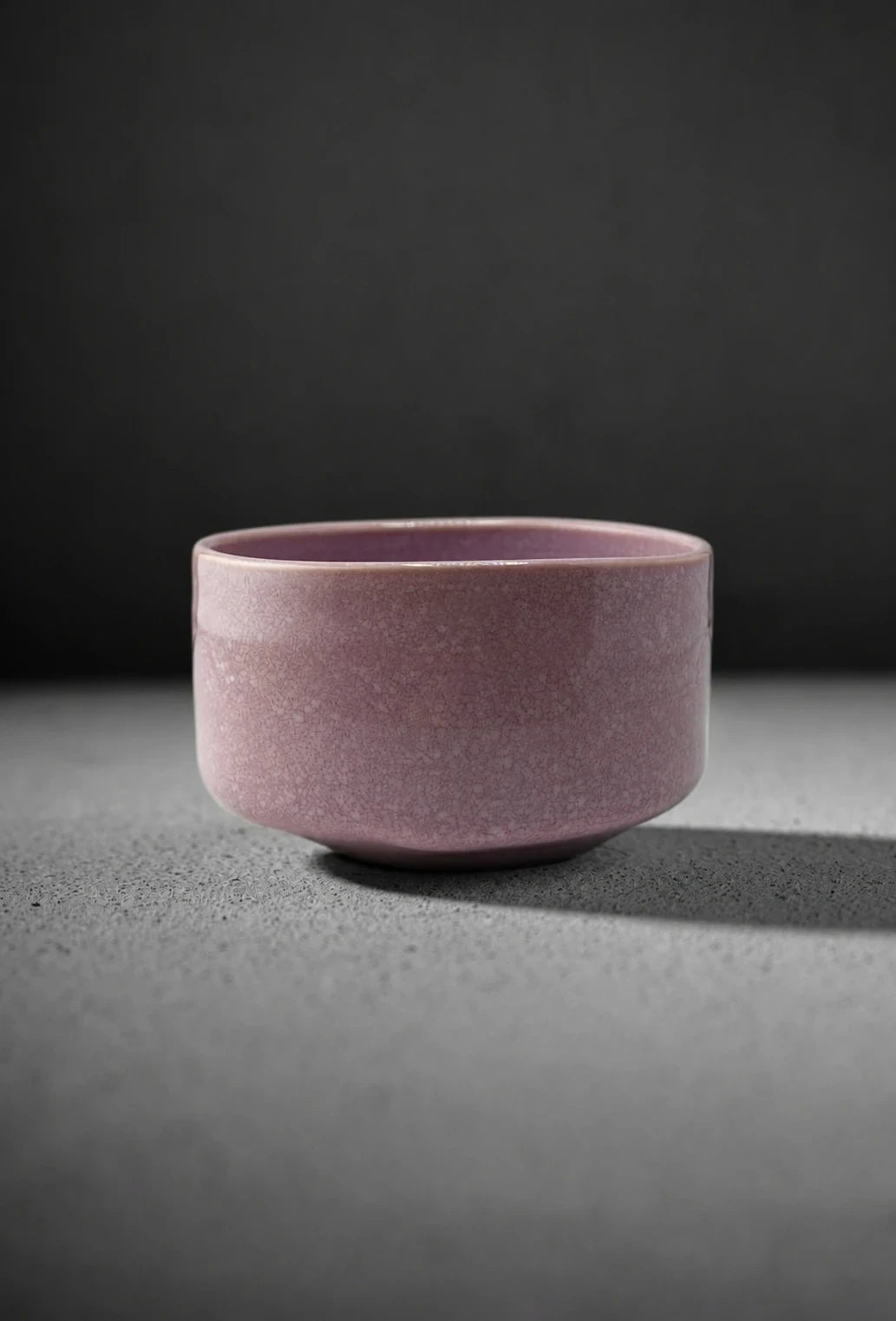 Shin Fuji matcha bowl in soft pink crackle glaze on dark grey studio background